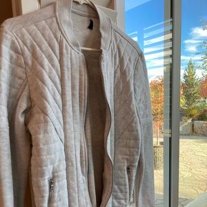 White small comfy jacket with pockets on side and zippers.